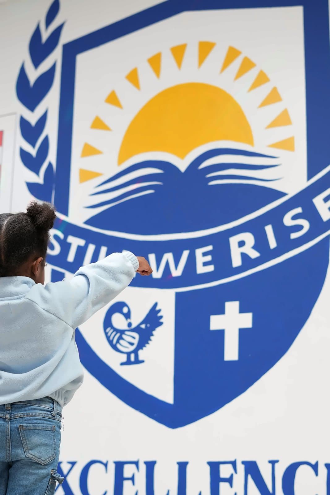 A SWREA student beside the Still We Rise crest