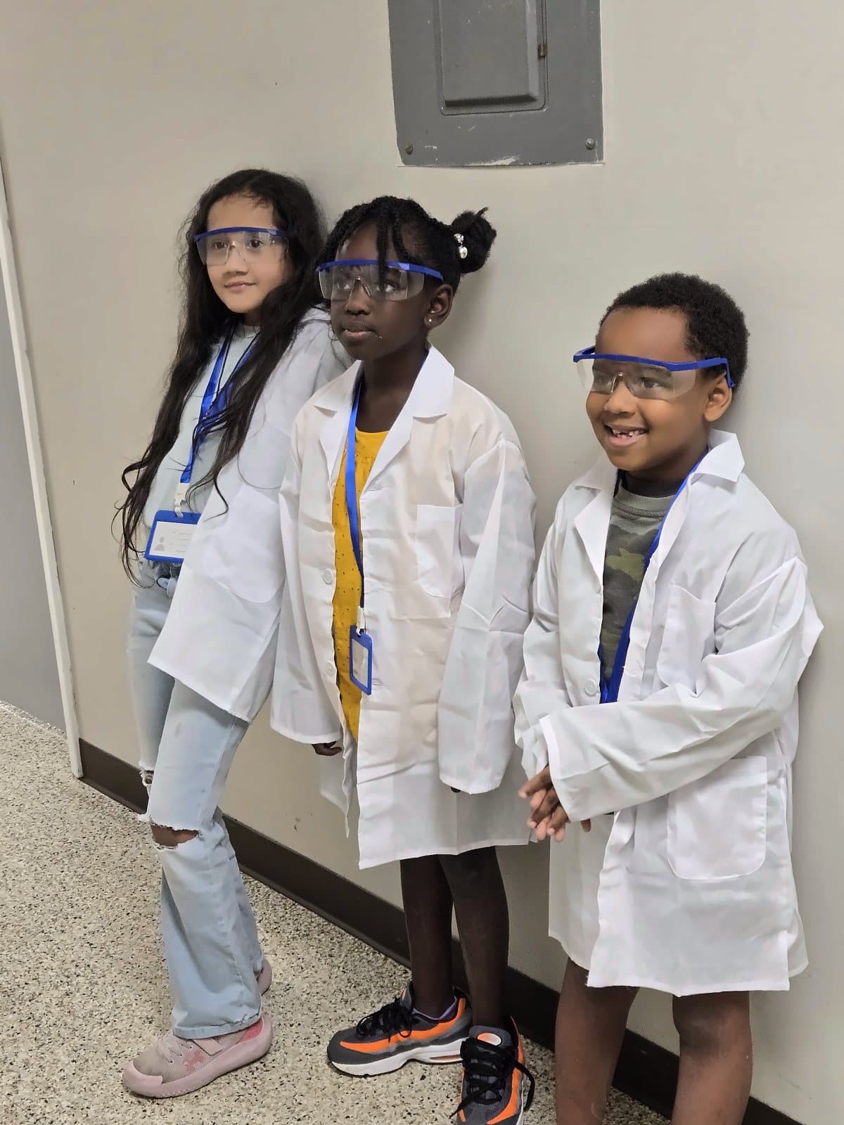 Three SWREA students in lab coats and safety goggles