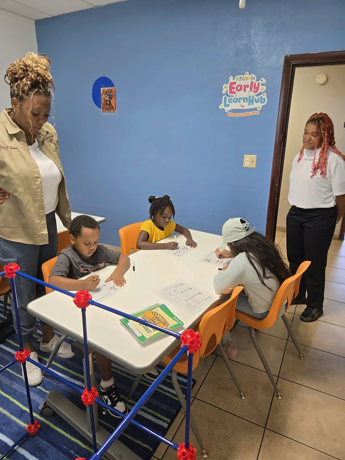 Ms. Jayla and SWREA staff standing with students working at a classroom table