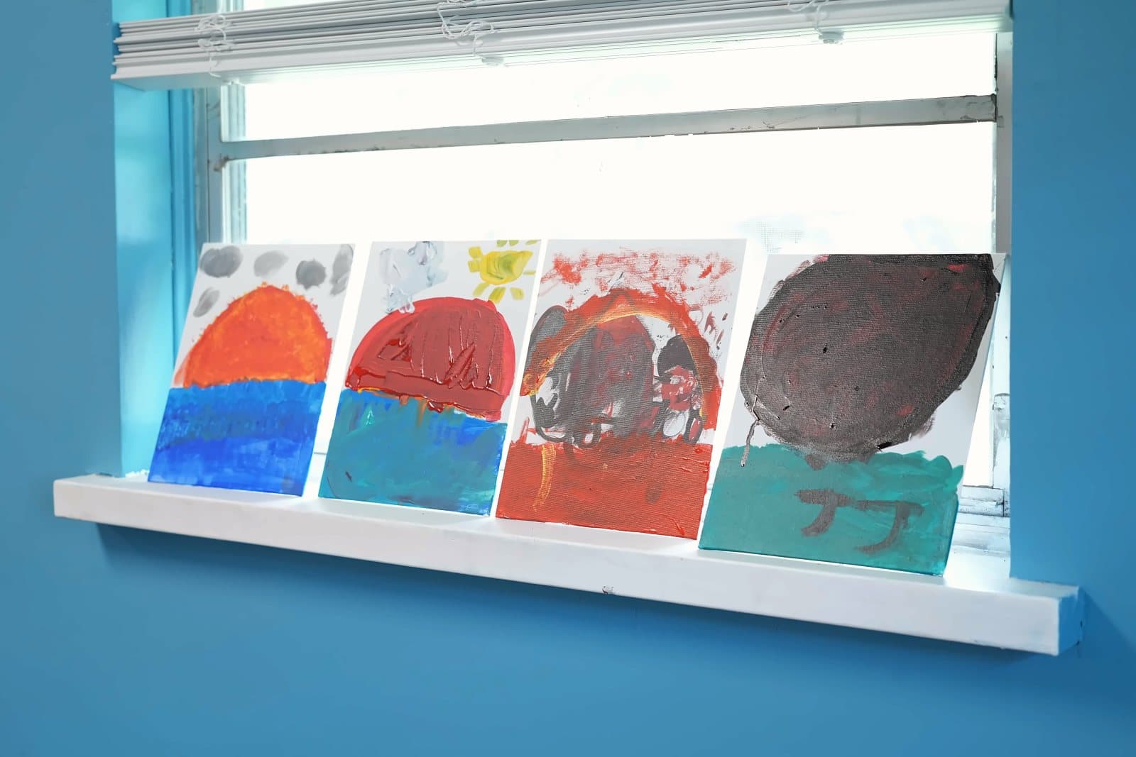 Paintings by SWREA students drying on a classroom windowsill