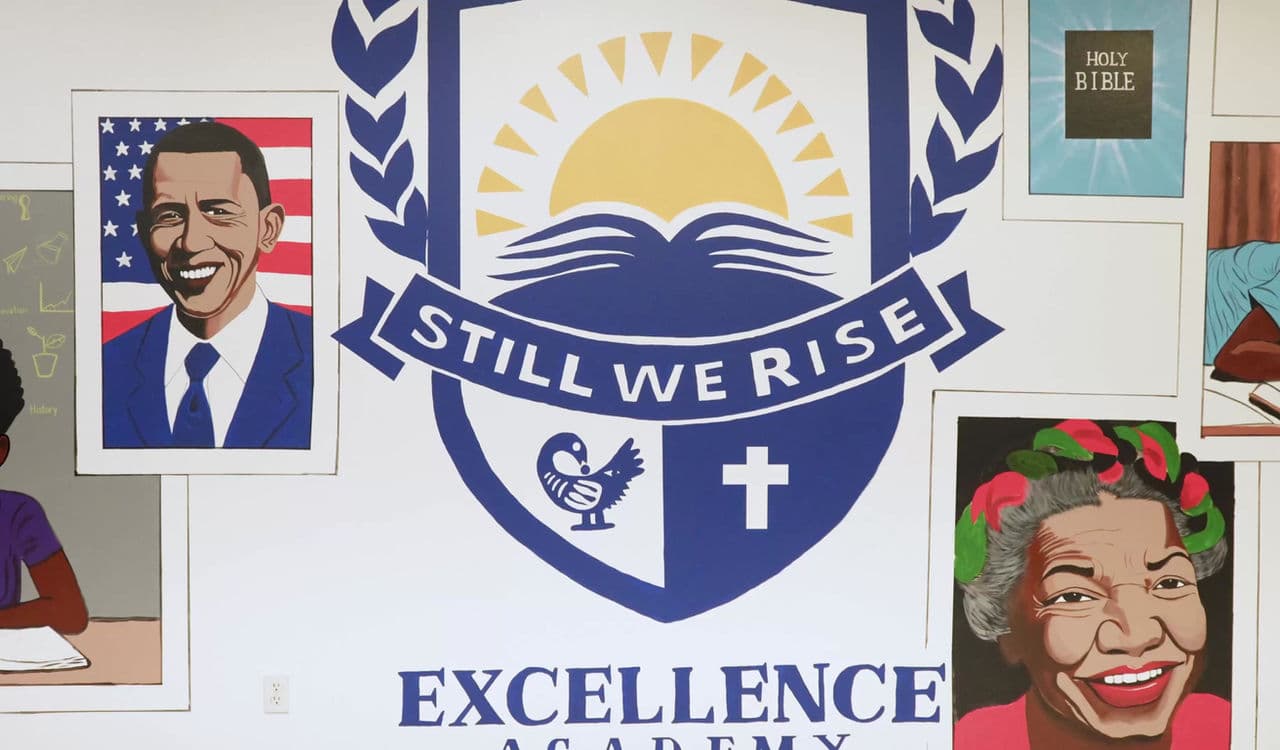 The Still We Rise shield painted on the wall at SWREA, surrounded by portraits